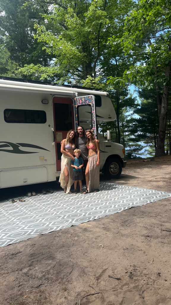 A family photo by a rv in a beautiful campsite by a lake in Michigan by Adventurous Leila.