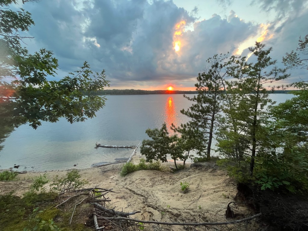 A photo of a pretty sunset at a campsite on a lake in Michigan by Adventurous Leila.