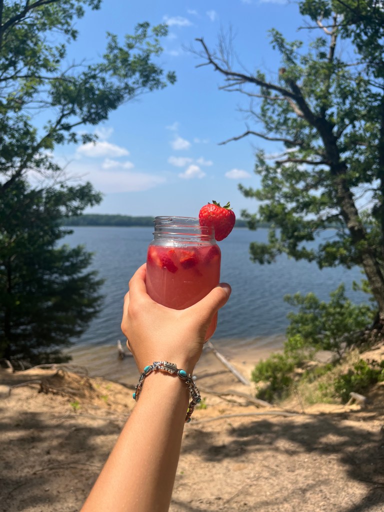 A person holding a yummy drink at the lake in Michigan by Adventurous Leila.