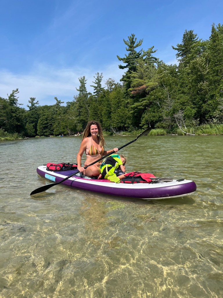 People having a good time paddle boarding on a spring to lake Michigan in Michigan by Adventurous Leila.