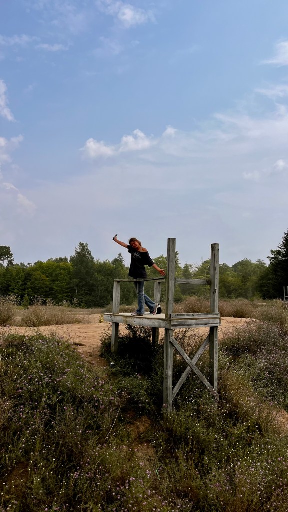 A Girl hangout out with a ton of their teen friends at an abandoned dirt bikes track at a super fun bus travel family friendly event called Skoolie U.P. in the upper peninsula of Michigan. By Adventurous Leila.