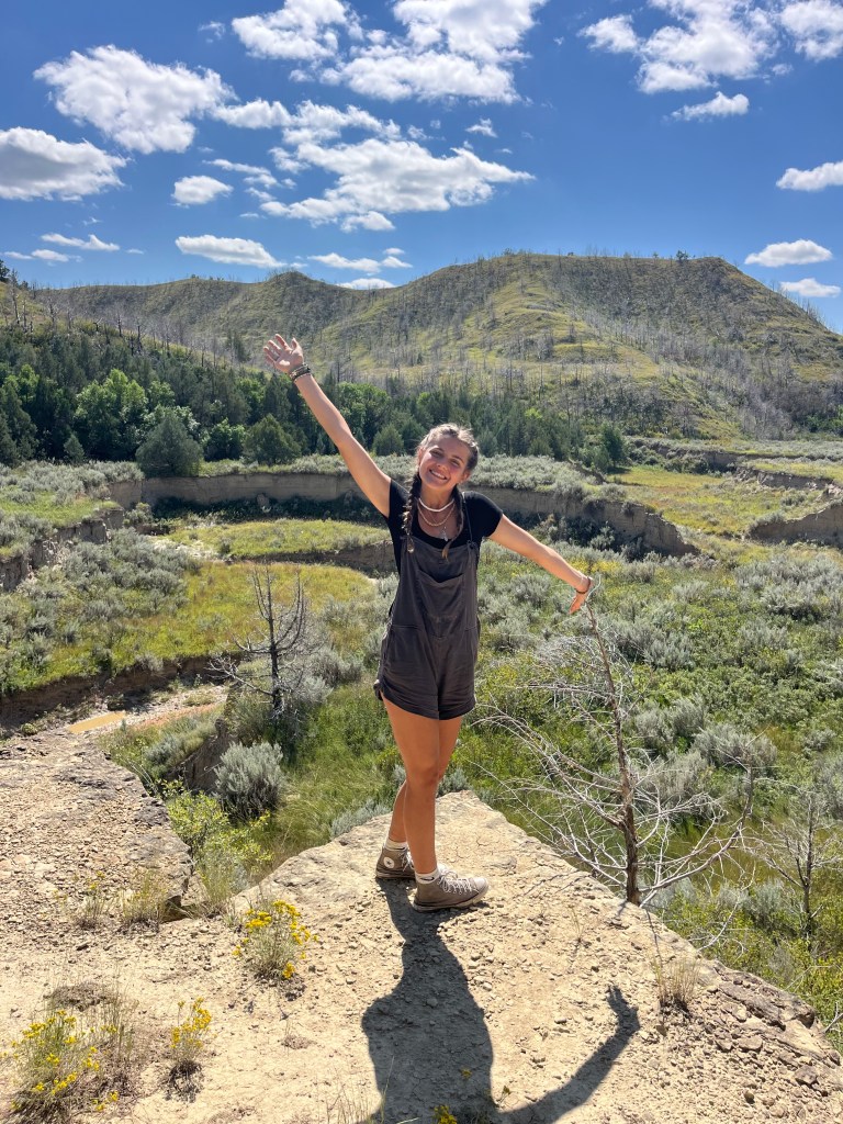 A photo of a girl taking a photo on a hike at Theodore Roosevelt national Park. By Adventurous Leila.