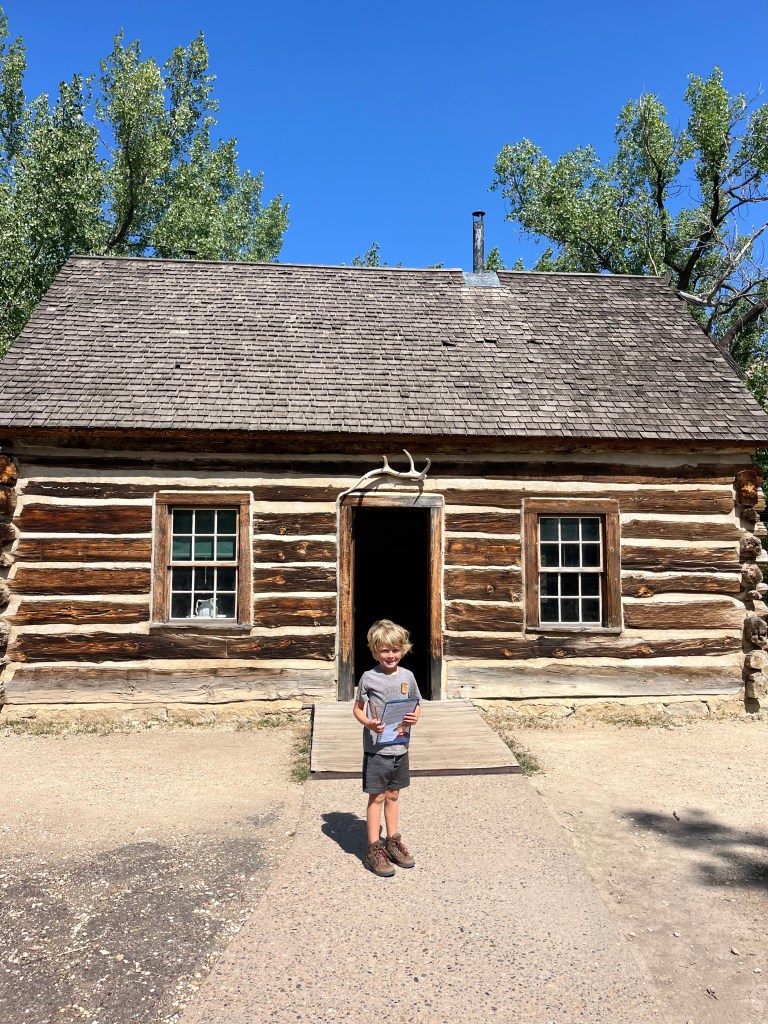 A photo of a little boy taking a photo on a hike at Theodore Roosevelt national Park at Theodore Roosevelt‘s house. By Adventurous Leila.